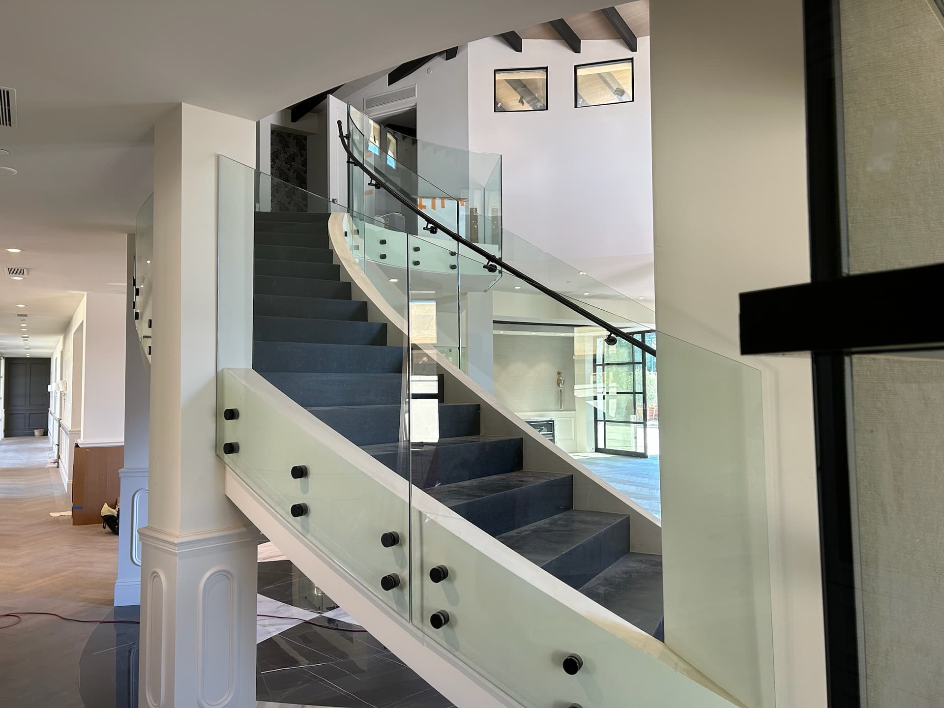 Curved glass railing with black rod handrail