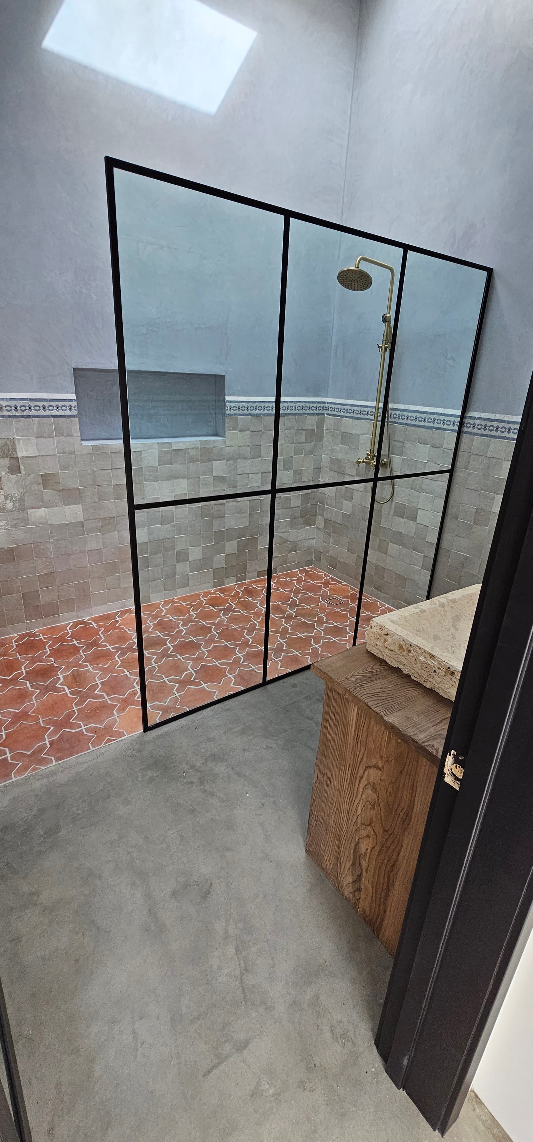 Steel-frame grid shower screen with terracotta floor